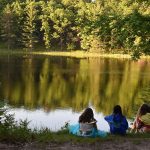 Campers sitting by lake