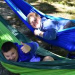 Two boys both laying in hammocks